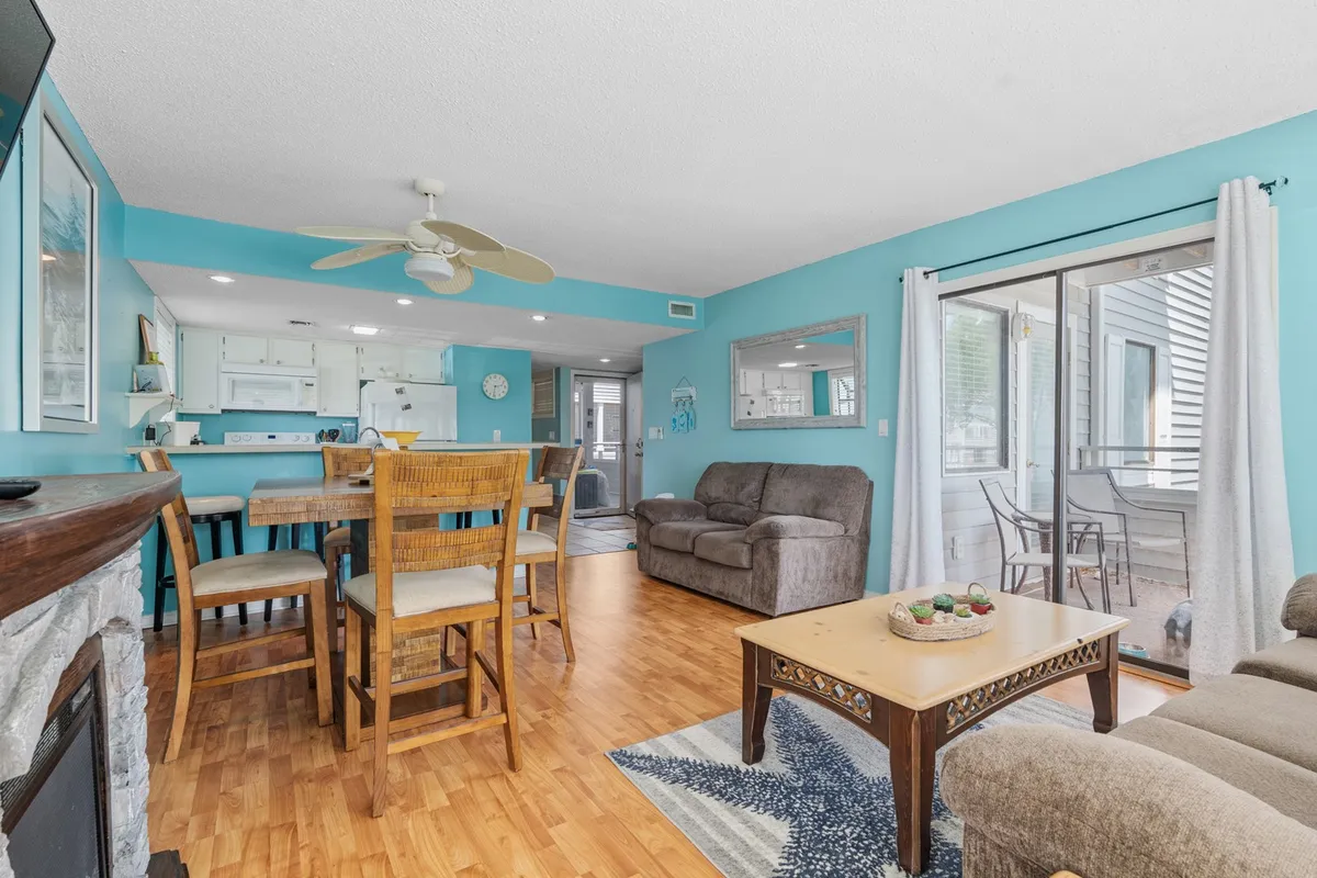 A thoughtfully designed living and dining space, with a comfy couch, coffee table, and a dining table set near a sliding glass door that opens onto a private balcony, emphasizing the open layout and connection to the outdoors.